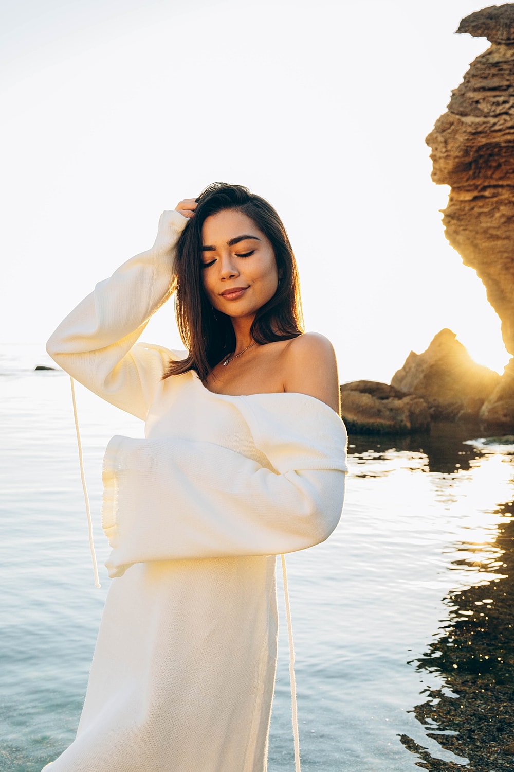 Newport Beach plastic surgery model in white dress by the water at sunset