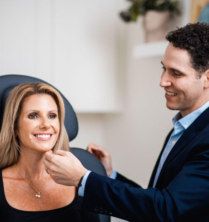 Newport Beach facial plastic surgery patient smiling in consultation with professional.