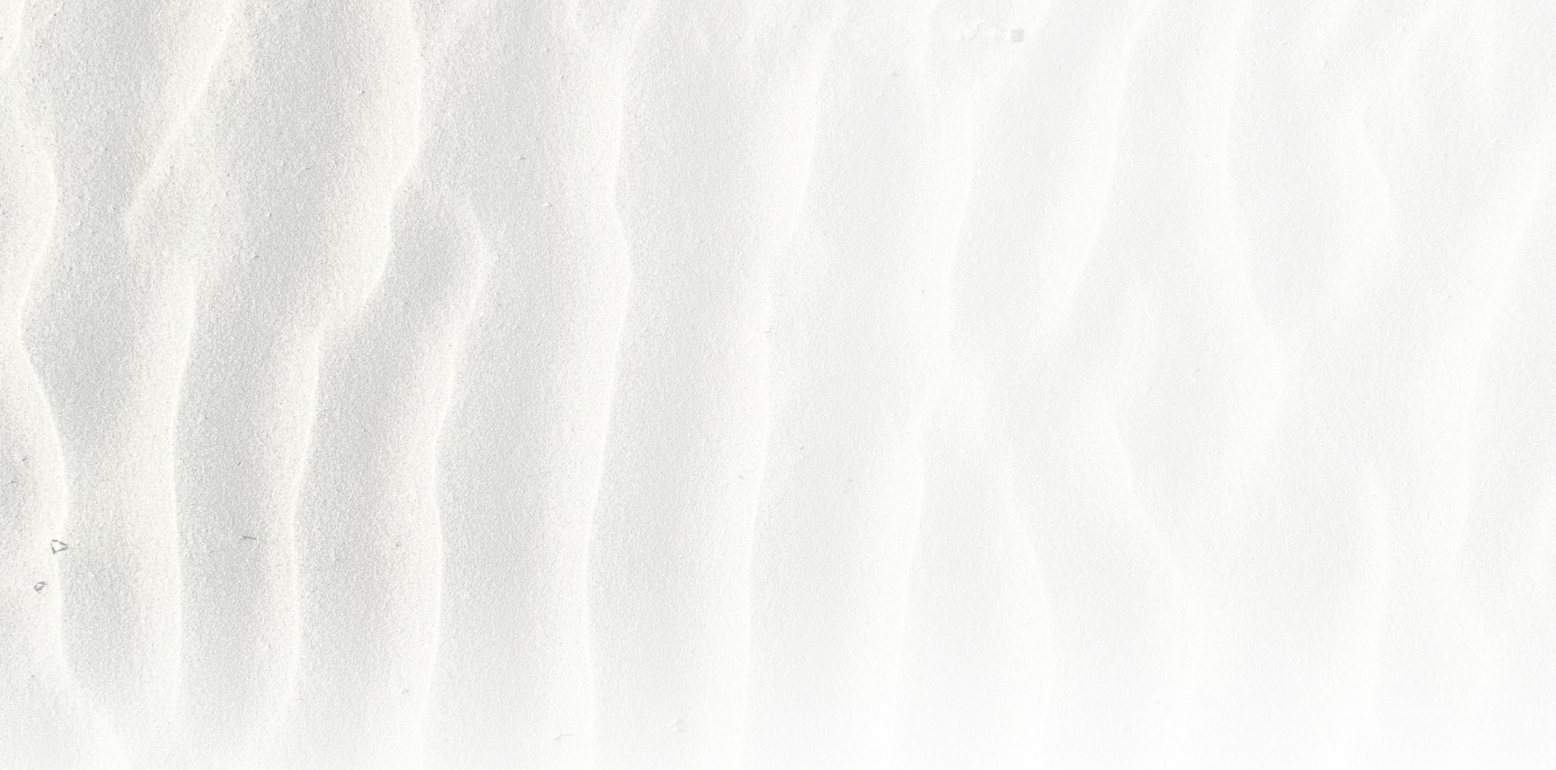 Textured white sand surface with gentle wave patterns.
