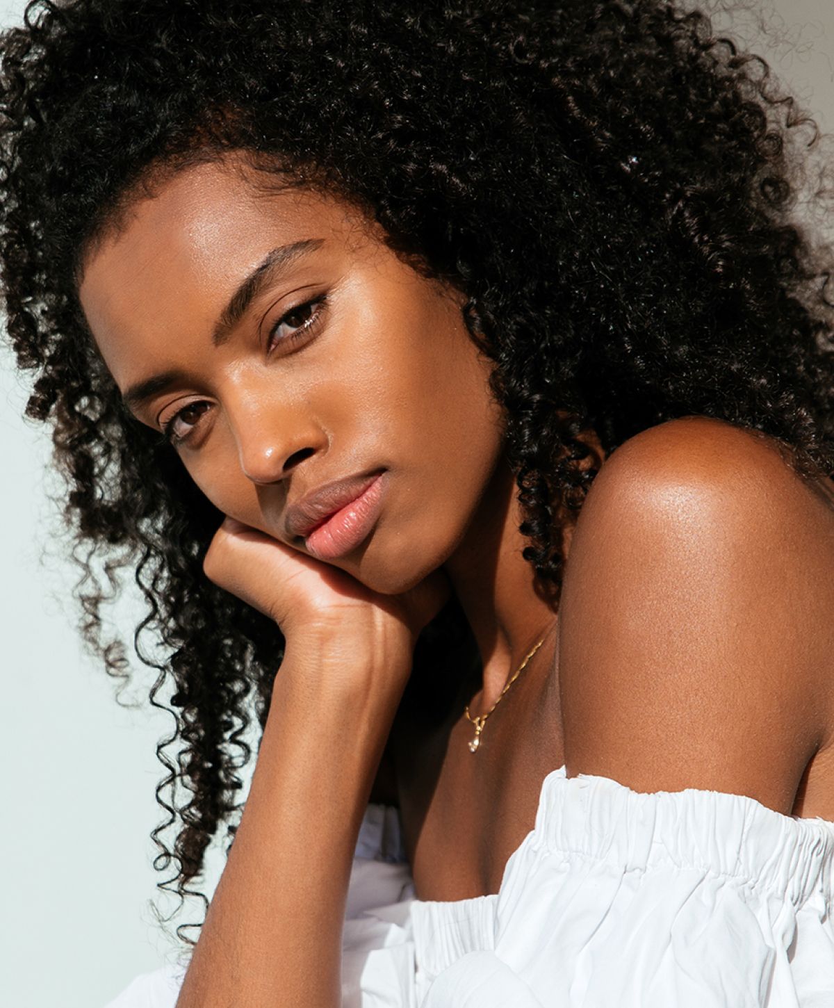 Newport Beach rhinoplasty model with curly hair resting her chin.