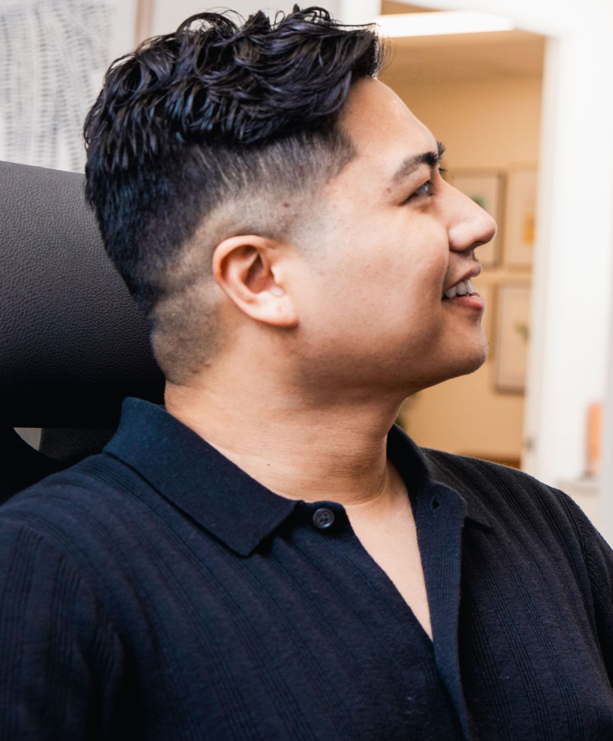 Newport Beach scar revision model smiling while seated in a modern setting.