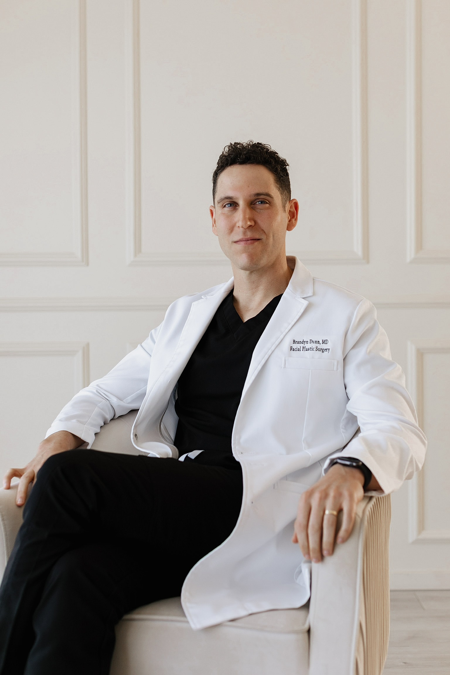 Newport Beach facial plastic surgeon in a suit with framed artwork.