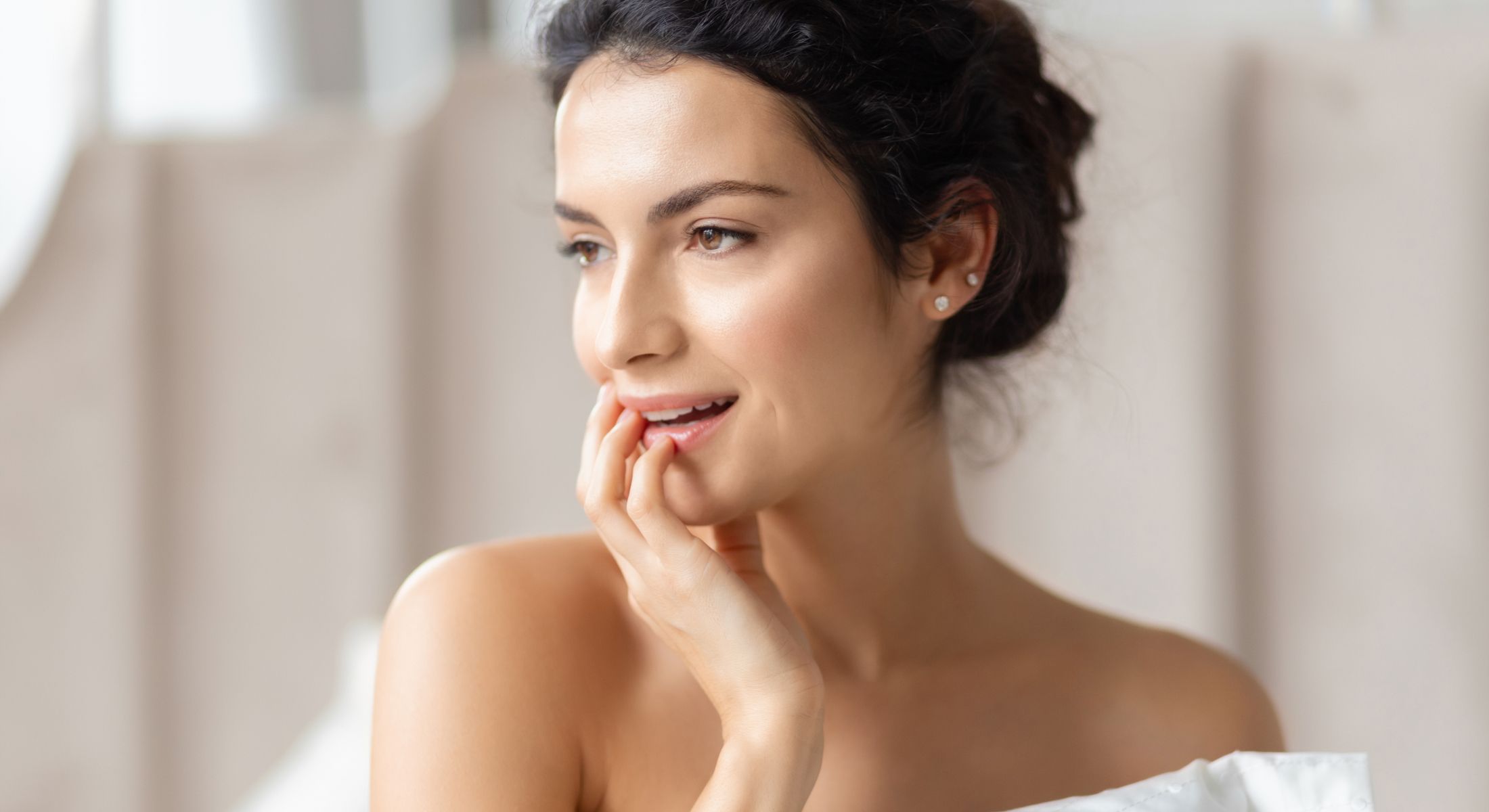 Newport Beach rhinoplasty model smiling and touching her face gently.